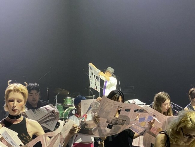 Art performance invites 100 participants to read newspapers on stage